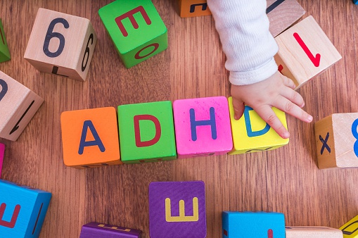 a gyermekek betűkockái, az ADHD név formájára elrendezve, a gyermek kezével